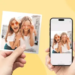 Dwie uśmiechnięte dziewczyny w okularach, zdjęcie do wywołania w Rossmannie, obok ekran telefonu z tym samym ujęciem.