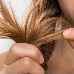 Mujer examinando su cabello fino, buscando soluciones para aumentar densidad capilar mujer.