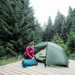 Une femme prépare son sac à dos près d'une tente dans une forêt de sapins. Une scène de camping en Allemagne.