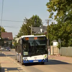 Autobus linii 134 z napisem "ZOO" jedzie ulicą w Krakowie, wśród zieleni i domów.