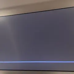 Szary ekran telewizora z niebieskim paskiem postępu i ikoną mikrofonu. Czekam na air play.