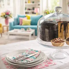 Patera do owoców z ciastami i babeczkami pod szklaną pokrywą, na stole w salonie.