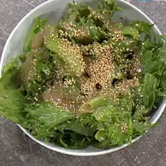 Grön, krispig sallad med sesamfrön och en dressing, perfekt som sallad till paj.