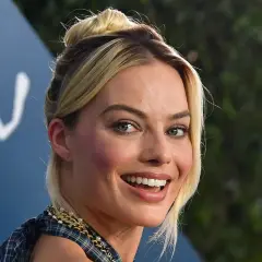 Margot Robbie, l'actrice qui incarne Harley Quinn, rayonne avec un chignon blond et un sourire éclatant.