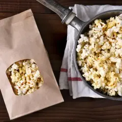 Jak zrobić popcorn w garnku? Świeżo przygotowany popcorn w garnku i papierowej torbie, gotowy do chrupania.