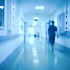 Un medico ospedaliero cammina in un corridoio. Chissà quanto prende di pensione dopo anni di servizio.