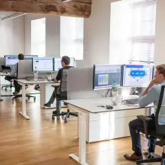 Bureau moderne avec employés travaillant sur des ordinateurs. Un homme utilise un service de bureau cloud pour gérer des données.