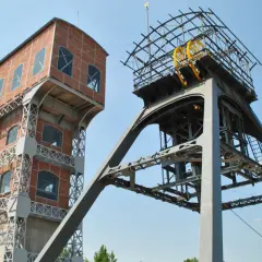 Dwie wieże kopalniane, jedna ceglana, druga metalowa z kołem, tworzą futurystyczny grawitacyjny magazyn energii.