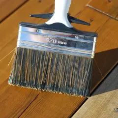 Pensel applicerar olja på altanen. Perfekt temperatur för att olja altanen.