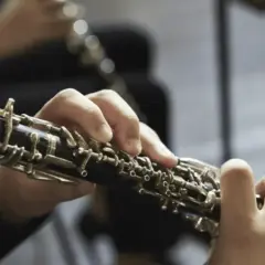Mains jouant d'un hautbois, un instrument à vent aux clés complexes, évoquant la musique classique.