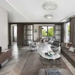 Elegancki salon z kanapą, fotelami i stolikiem kawowym. W tle widać jadalnię i okno z widokiem na zieleń. Całość emanuje wyrafinowanym, **włoskim stylem**.