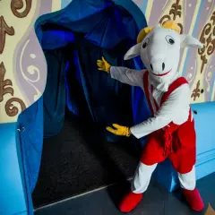 Maskotka owieczki zaprasza do wejścia, odkrywając tajemnicze przejście. To jedna z wielu atrakcji w Pacanowie, które czekają na odkrycie.