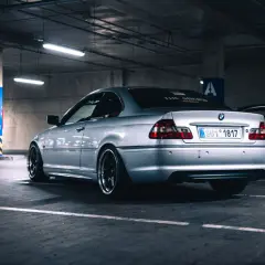 Srebrne BMW serii 3 (m54) z przyciemnianymi szybami i czarnymi felgami stoi na parkingu podziemnym.