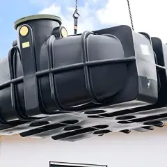 Schwarzer Tank wird mit Kran gehoben, bereit zum zisterne einbauen.