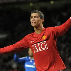 Cristiano Ronaldo w czerwonej koszulce Manchesteru United, z uniesionymi rękami, świętuje bramkę. To był kluczowy moment przed jego transferem.
