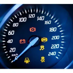 Cruscotto auto con tachimetro e spie accese: spia punto esclamativo giallo, ABS, controllo stabilità e batteria.