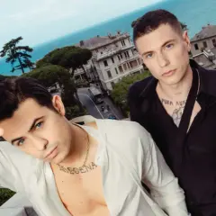 Benji e Fede posano con un panorama mozzafiato alle loro spalle, tra case colorate e il blu del mare.