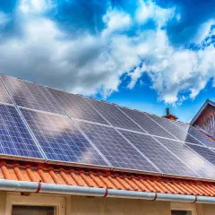 Panneaux solaires sur un toit de tuiles rouges, sous un ciel bleu et nuageux. Une installation qui assure une garantie pour l'avenir.