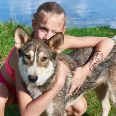 Dziewczynka mocno przytula swojego ukochanego psa kundla. Na jej ramieniu widnieje napis "LOVE".