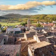 Panoramica di Sarteano cosa vedere: tetti in cotto, campanile e colline verdi sotto un cielo nuvoloso.
