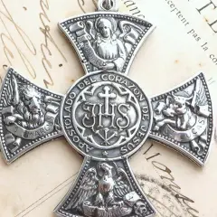 Srebrny medalion z symbolem IHS i symbolami ewangelistów: lew (św. Marek), anioł (św. Mateusz), wół (św. Łukasz) i orzeł (św. Jan).