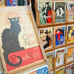 Affiches de chat art, dont une grande affiche du Chat Noir, exposées sur un présentoir en bois.