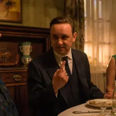 Scena z filmu Marka Koterskiego: mężczyzna w garniturze gestykuluje do kobiety w zielonej sukience, obok siedzi starsza pani.