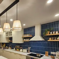 Una lámpara negra y madera ilumina esta cocina moderna con azulejos azules y encimeras de mármol.