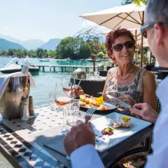 Un couple savoure un repas gastronomique avec vue sur le lac d'Annecy. La plage est magnifique.