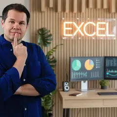 Mężczyzna zastanawia się, jak zrobic wykres w Excel. Na biurku dwa monitory z danymi i wykresami.