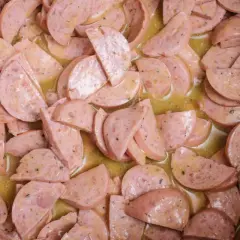 Scheiben von Lyoner Wurst in einer gelben, würzigen Soße, bereit für einen herzhaften Wurstsalat.