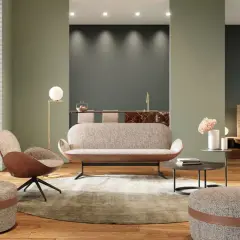 Modernes Wohnzimmer mit einem stilvollen Sofa als Raumteiler. Ein Sessel, Hocker und ein Kamin schaffen Gemütlichkeit.