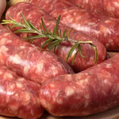 Surowe kiełbaski, czyli salsiccia, z gałązką rozmarynu i czosnkiem. Idealne do grillowania.