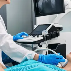 Lekarz wykonuje USG szyi pacjentki, badając potencjalne uszkodzenie nerwu krtaniowego po operacji tarczycy.