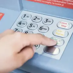 Dłoń wpisuje PIN na bankomacie, by sprawdzić, czy nie ma debetu na koncie.