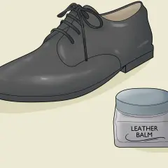 Un soulier en cuir noir et un pot de baume pour cuir. Apprenez comment assouplir des chaussures en cuir pour un confort optimal.