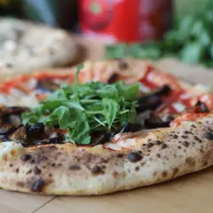 Eine köstliche neapel pizza mit Auberginen und Rucola, frisch aus dem Ofen.