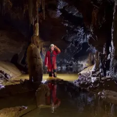 Eksplorator w jaskini, zanurzony po kolana w wodzie, odkrywa tajemnice speleologii.