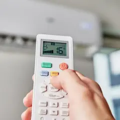 Main tenant effectue le réglage clim télécommande pour une température de 16°C.