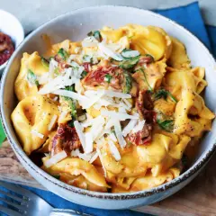 Cremige Tortellini mit Spinat und getrockneten Tomaten, bestreut mit Parmesan. Ein köstliches Gericht, das Lust auf mehr Tortellini Rezepte macht.
