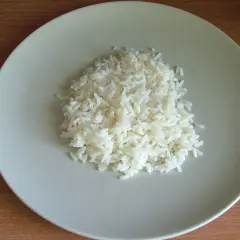 Ugotowany ryż na jasnoszarym talerzu.