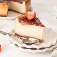Deliciosa tarta de queso vegana con cobertura de fresa y una fresa fresca encima.