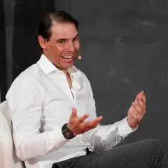 Rafael Nadal, znany z imponującego majątku, w białej koszuli, z uśmiechem i gestykulując.
