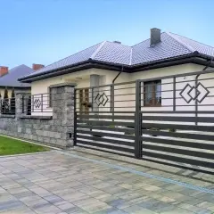 Nowoczesne rodzaje bram wjazdowych z metalu, z kamiennym ogrodzeniem i podjazdem z kostki.