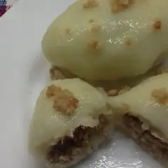 Pyszne pyzy z mięsem, gotowe do jedzenia. Jedna pyza jest przekrojona, ukazując soczyste nadzienie.