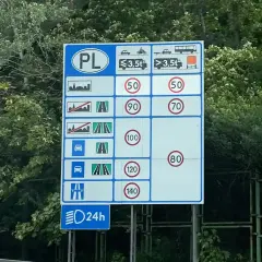 Znak drogowy w Polsce informuje o limitach prędkości na autostradzie dla różnych pojazdów i warunków.