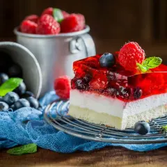 Pyszny deser z galaretką i owocami leśnymi. Zastanawiasz się, ile czasu stygnie galaretka? Ten kawałek ciasta wygląda idealnie!
