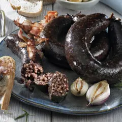 Kaszanka po śląsku na talerzu z chlebem, boczkiem i pieczoną cebulką.