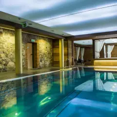 Basen w hotelu Aubrecht Country Spa Resort Koprzywnica. Woda w basenie ma piękny, turkusowy kolor, a ściany zdobi kamień i drewno.