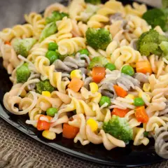 Deliciosa ensalada de pasta vegana con brócoli, guisantes, zanahoria y maíz. Un plato colorido y saludable.